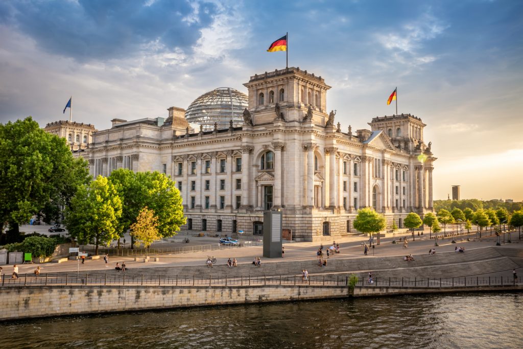 Reichstagsgebäude mit Glaskuppel an der Spree im Abendlicht.