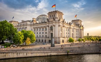 Reichstagsgebäude mit Glaskuppel an der Spree im Abendlicht.