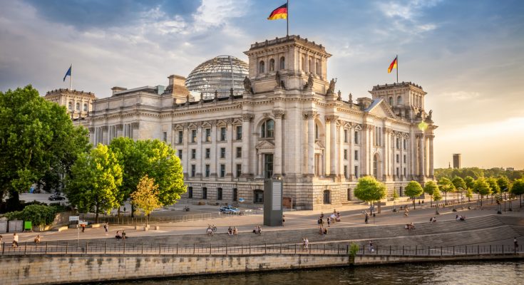 Reichstagsgebäude mit Glaskuppel an der Spree im Abendlicht.
