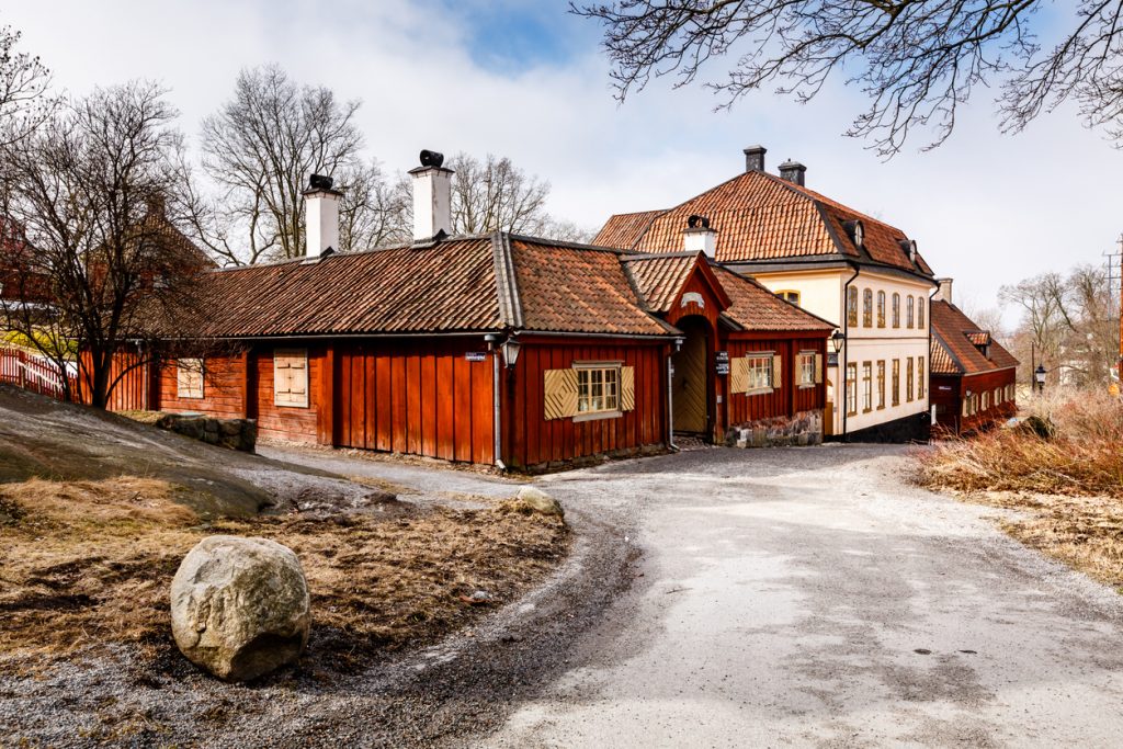 Rote Holzgebäude mit Ziegeldächern im Skansen-Freilichtmuseum in Stockholm.