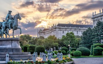 Denkmal Maria Theresias mit Gartenanlagen und klassischer Architektur im warmen Abendlicht.