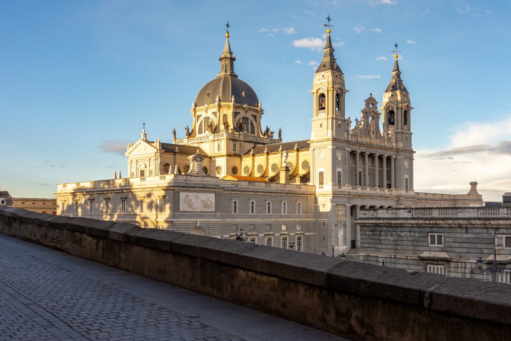 Blick auf Kuppel und Türme der Almudena-Kathedrale in Madrid bei Sonnenuntergang.