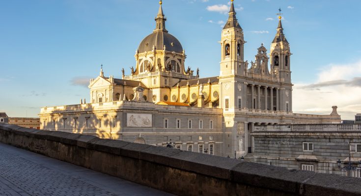 Blick auf Kuppel und Türme der Almudena-Kathedrale in Madrid bei Sonnenuntergang.