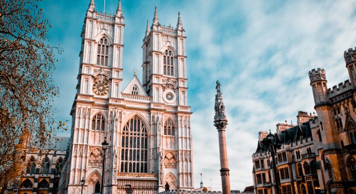 Gotische Abteikirche mit Doppeltürmen vor blauem Himmel.