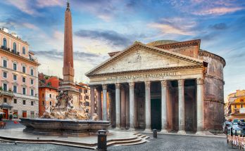 Pantheon mit korinthischer Säulenfront und Brunnen samt Obelisk bei Abendhimmel.