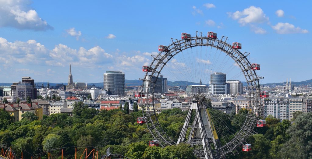Riesenrad im Wiener Prater vor Skyline mit Stephansdom und Hochhäusern.
